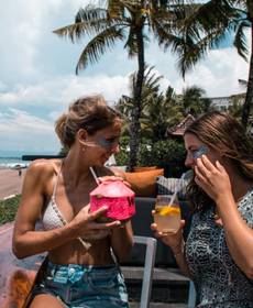 Zwei Freundinnen in der Strandbar mit wiederverwendbaren Augenmasken im Gesicht