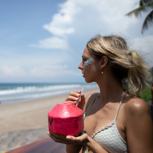 Frau am Strand mit Kokusnuss und Augenpads 