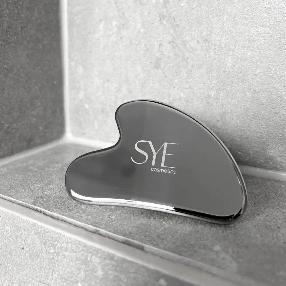 Gua Sha Stein aus Edelstahl im Badezimmer präsentiert, bereit zur Guasha Massage 